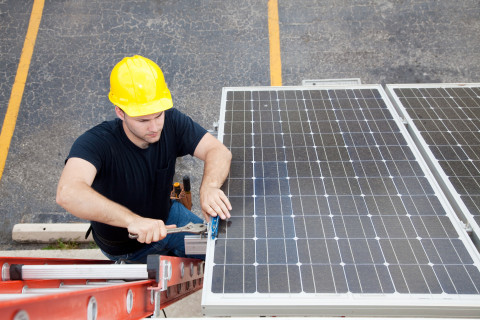Vue d'un homme dans un échelle en train d'installer une panneau solaire