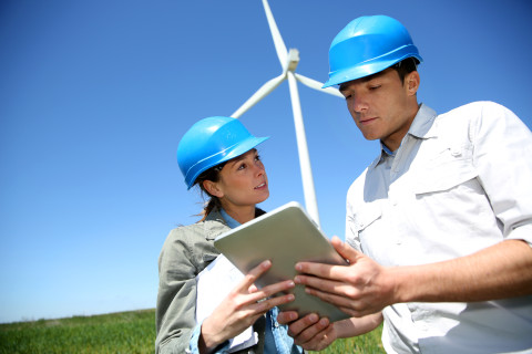 Vue d'un homme et d'une femme regarde une tablette devant une éolienne