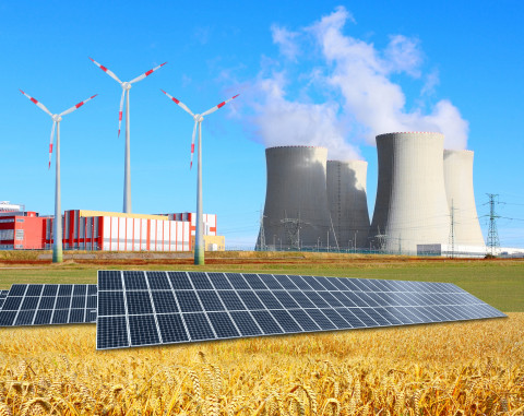 Vue d'un champ avec des panneaux solaires, des éoliennes et une usine. 